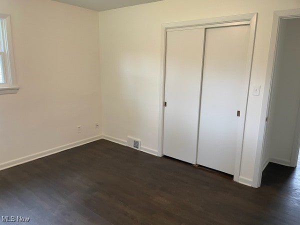 unfurnished bedroom with dark hardwood / wood-style floors and a closet