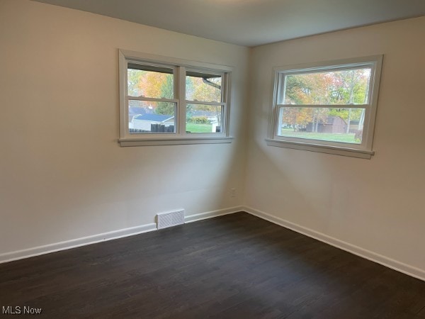 empty room with dark wood-type flooring and plenty of natural light