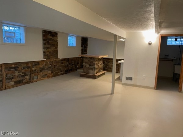 basement featuring a textured ceiling and a wealth of natural light