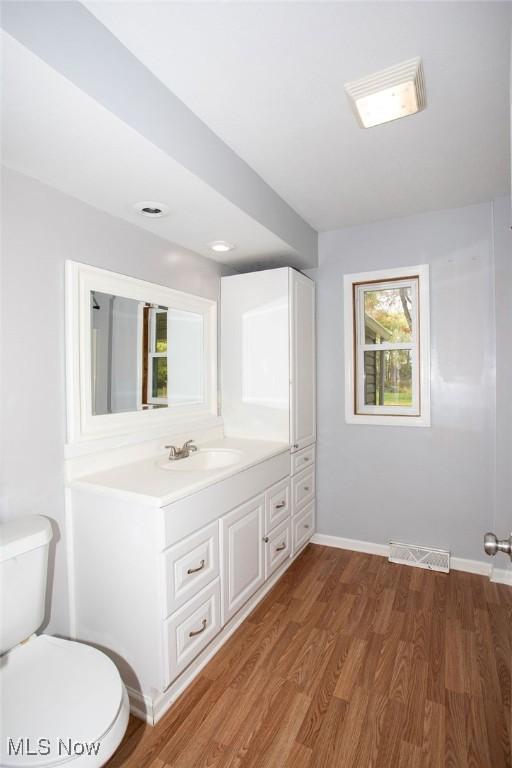 bathroom with toilet, vanity, and hardwood / wood-style flooring