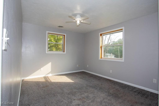 carpeted empty room with ceiling fan and plenty of natural light