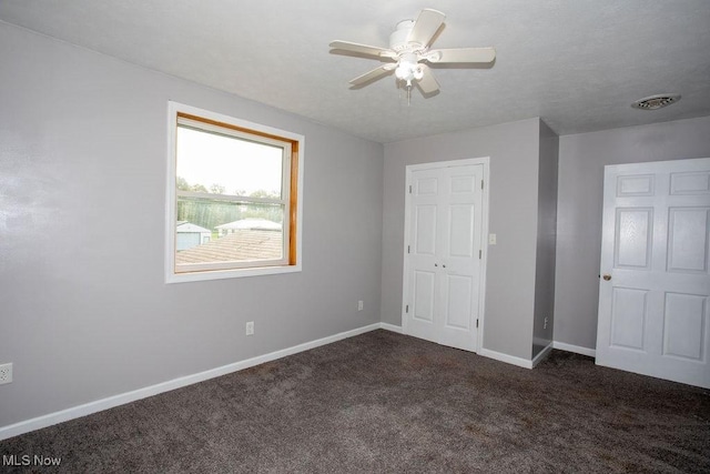 unfurnished bedroom with dark carpet and ceiling fan