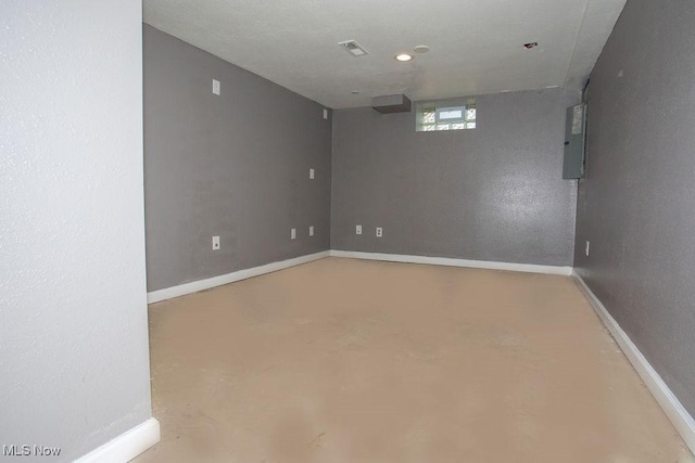 spare room with electric panel and concrete floors