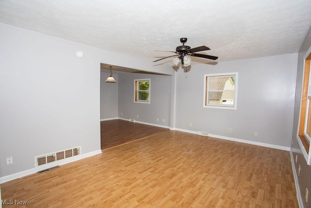 unfurnished room featuring a wealth of natural light, ceiling fan, and hardwood / wood-style flooring