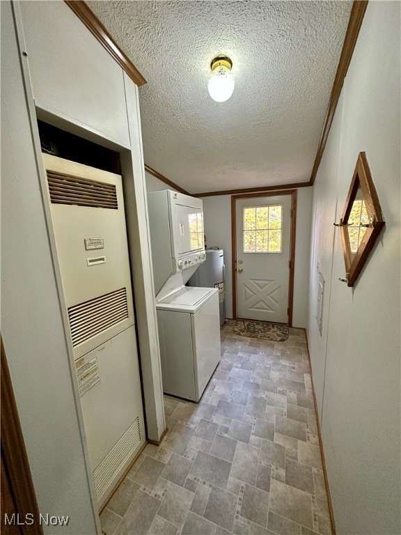 laundry area with crown molding, a textured ceiling, and stacked washer and clothes dryer