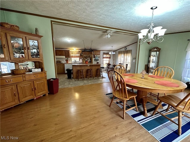 dining space with ornamental molding, light hardwood / wood-style flooring, a textured ceiling, and plenty of natural light