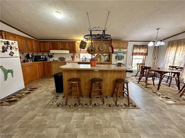 kitchen featuring white appliances, backsplash, a notable chandelier, and a textured ceiling