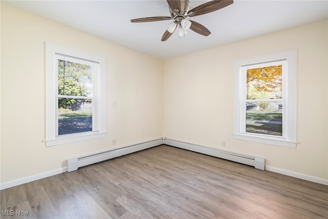 spare room with baseboard heating, ceiling fan, light wood-type flooring, and plenty of natural light