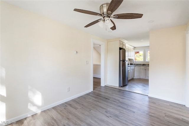 unfurnished living room with sink, light wood-type flooring, and ceiling fan