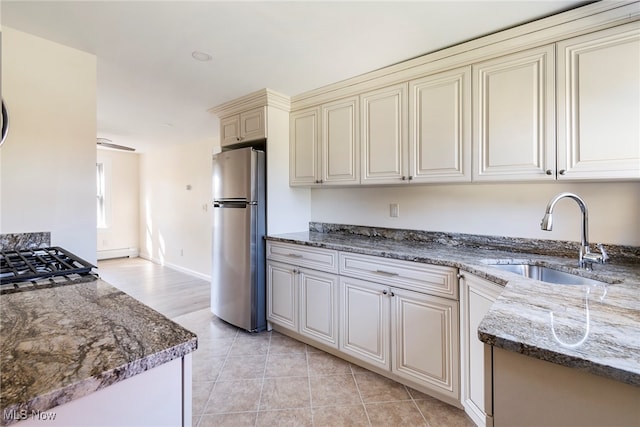 kitchen featuring stainless steel fridge, dark stone countertops, sink, and cream cabinetry