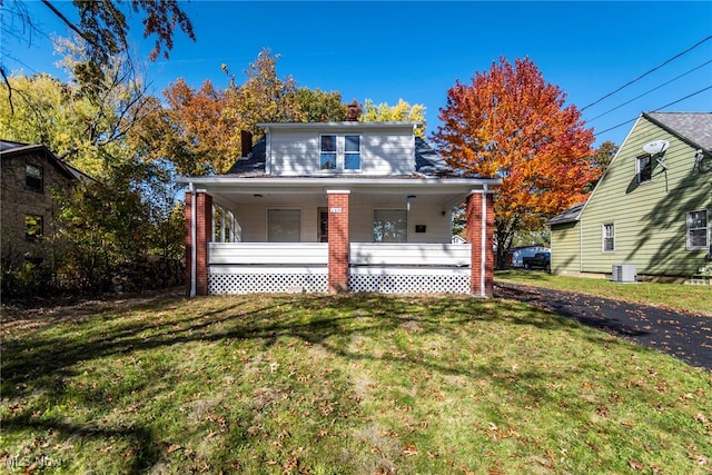 view of front of property featuring a front yard, cooling unit, and a porch