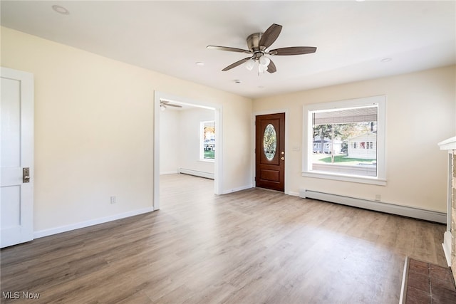 entrance foyer with light hardwood / wood-style floors, a baseboard radiator, a brick fireplace, and ceiling fan