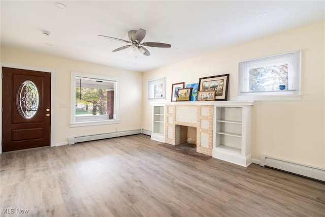 entryway with ceiling fan, wood-type flooring, a baseboard heating unit, and a fireplace