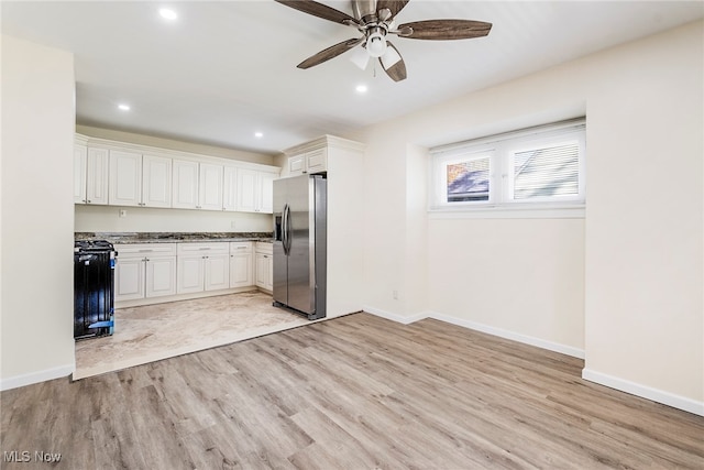 kitchen featuring black stove, white cabinets, stainless steel refrigerator with ice dispenser, and light wood-type flooring