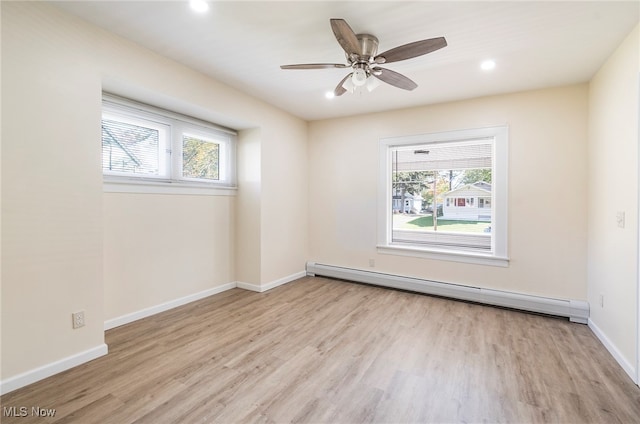 spare room with a baseboard radiator, light hardwood / wood-style flooring, ceiling fan, and plenty of natural light