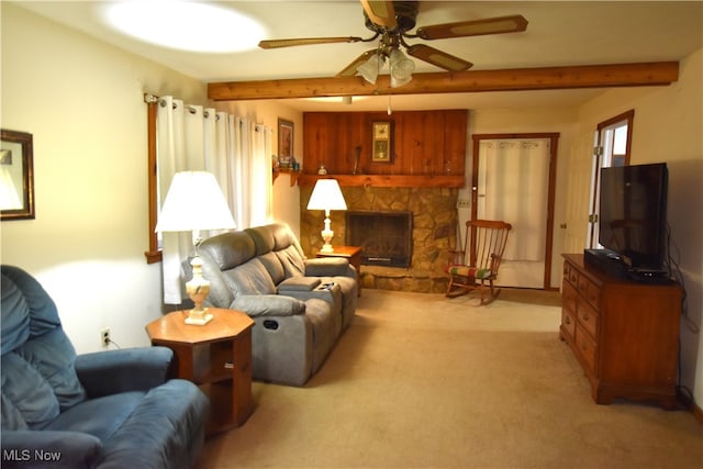 carpeted living room with beam ceiling, a stone fireplace, ceiling fan, and plenty of natural light