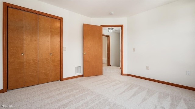 unfurnished bedroom with light colored carpet and a closet