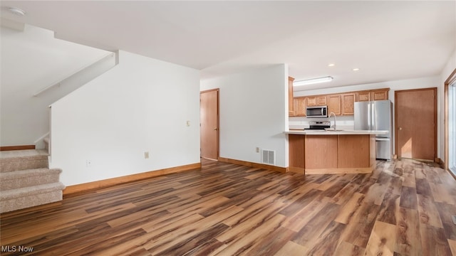 kitchen featuring kitchen peninsula, stainless steel appliances, wood-type flooring, and sink