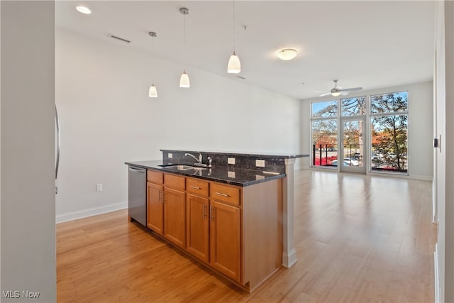 kitchen featuring sink, light hardwood / wood-style floors, dark stone counters, stainless steel dishwasher, and pendant lighting