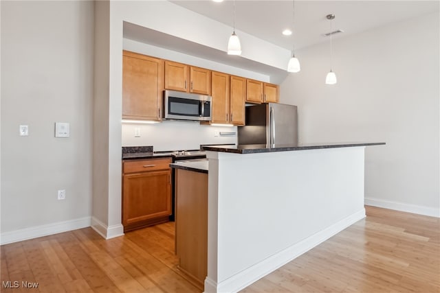 kitchen with a center island, decorative light fixtures, stainless steel appliances, and light wood-type flooring