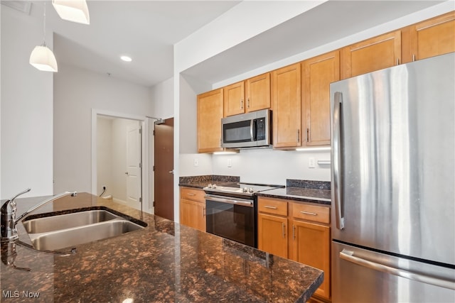 kitchen featuring stainless steel appliances, sink, dark stone counters, and pendant lighting