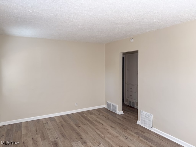 spare room with a textured ceiling and hardwood / wood-style floors