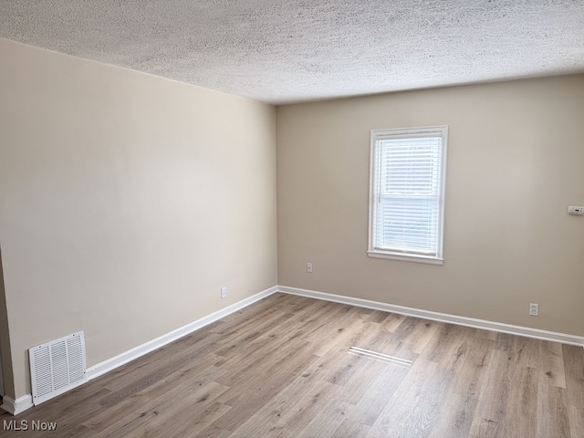 empty room featuring a textured ceiling and light wood-type flooring