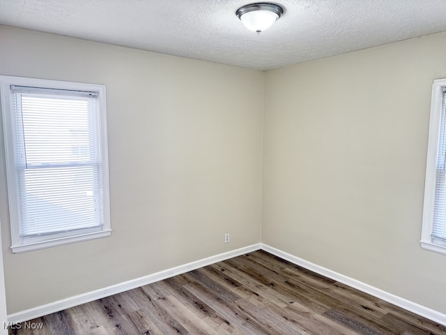 unfurnished room featuring wood-type flooring and a textured ceiling