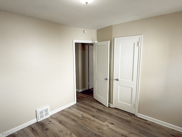 unfurnished bedroom featuring hardwood / wood-style flooring and a textured ceiling