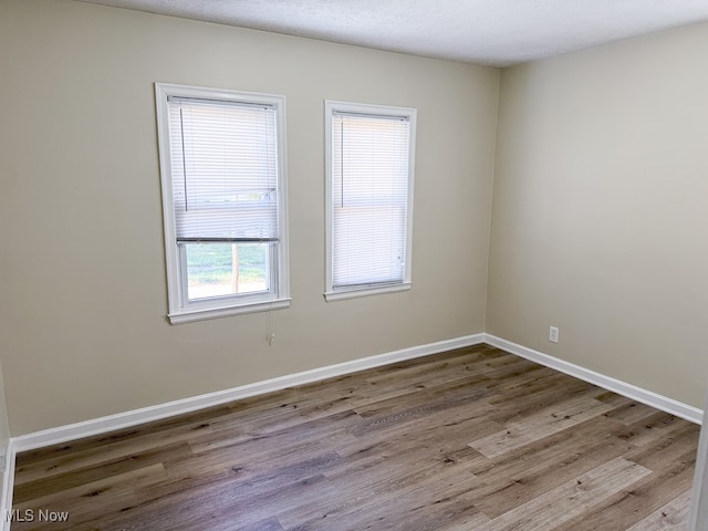 empty room with light hardwood / wood-style floors and a textured ceiling