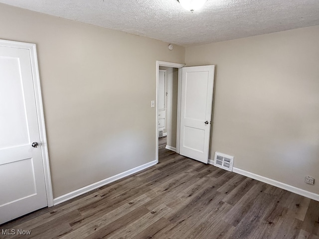 empty room featuring a textured ceiling and dark hardwood / wood-style flooring