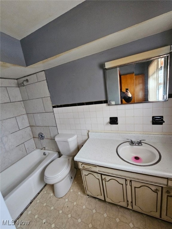 full bathroom featuring vanity, tiled shower / bath combo, toilet, and tile walls