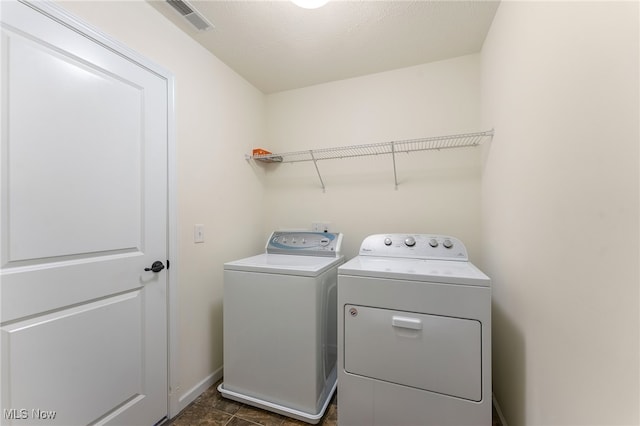 washroom with a textured ceiling, washing machine and clothes dryer, and dark tile patterned floors