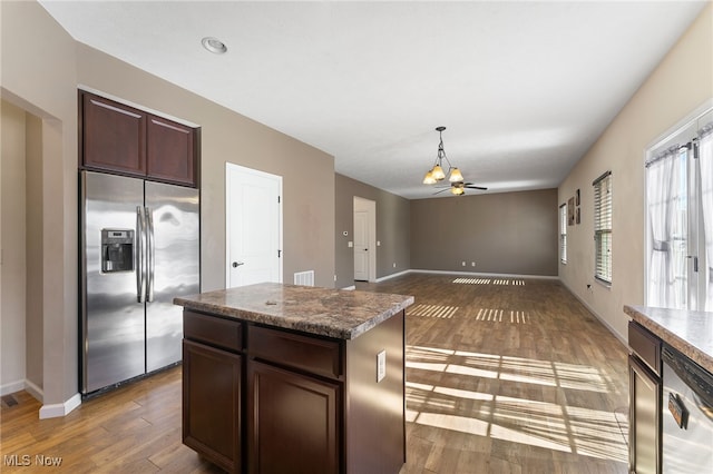 kitchen featuring appliances with stainless steel finishes, dark hardwood / wood-style floors, dark brown cabinets, and a kitchen island