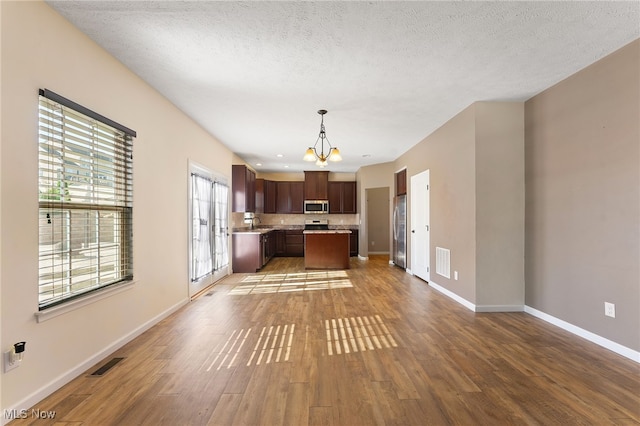 kitchen with hardwood / wood-style floors, stainless steel appliances, a notable chandelier, decorative light fixtures, and a center island