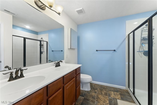 bathroom with toilet, a textured ceiling, vanity, and a shower with door