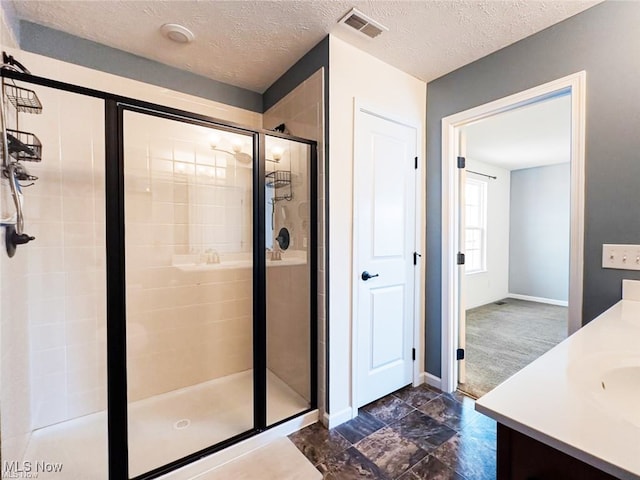 bathroom featuring a shower with door, a textured ceiling, and vanity