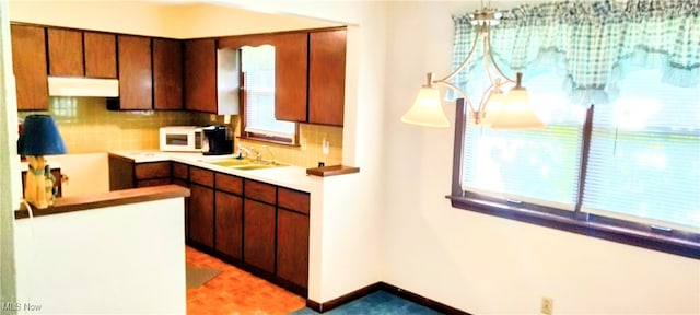 kitchen with decorative backsplash, a wealth of natural light, sink, and hanging light fixtures