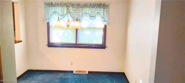 empty room with carpet floors and an inviting chandelier