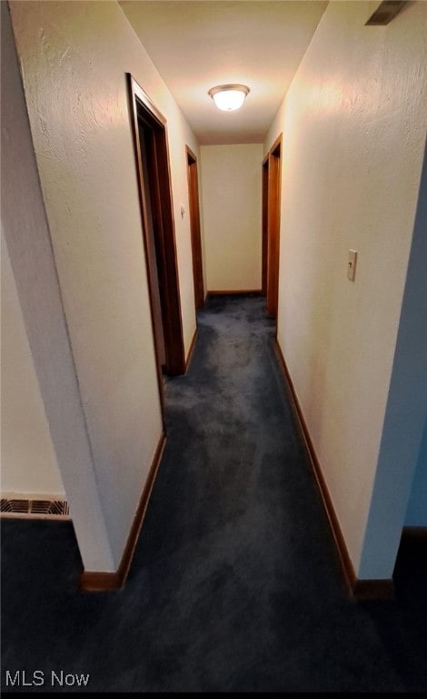 hallway with dark colored carpet