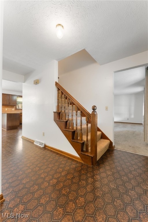 staircase featuring a textured ceiling