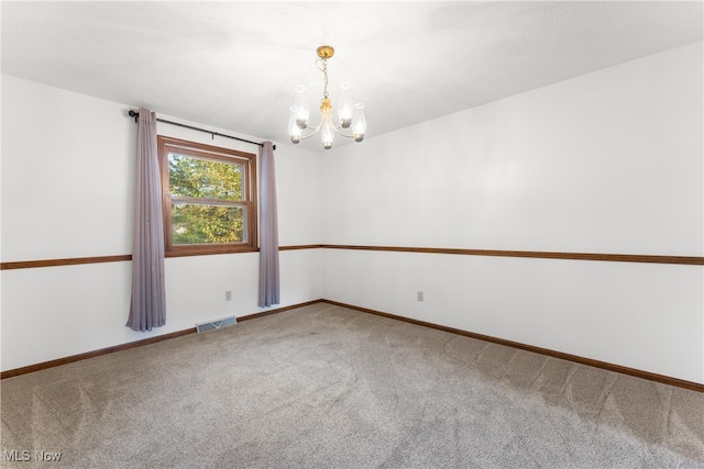 carpeted spare room featuring an inviting chandelier