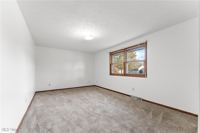 unfurnished room with a textured ceiling and light colored carpet