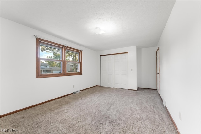 unfurnished bedroom with a closet, light carpet, and a textured ceiling