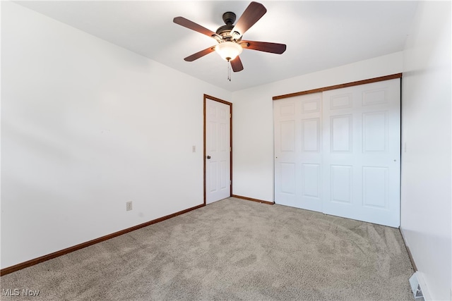 unfurnished bedroom with a closet, light colored carpet, a baseboard radiator, and ceiling fan