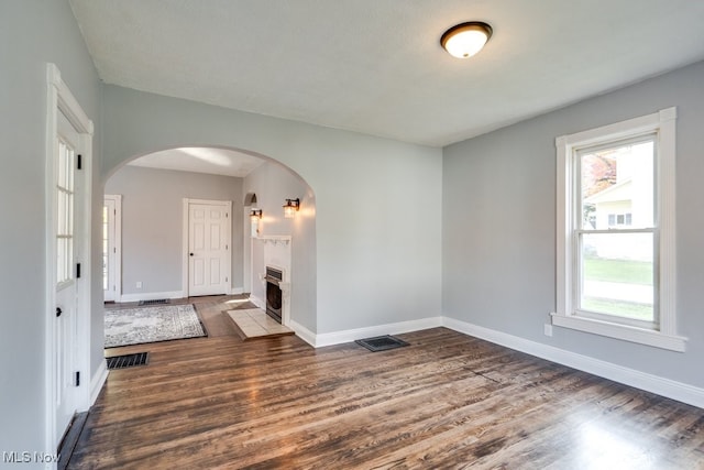 empty room with dark hardwood / wood-style floors, a textured ceiling, and plenty of natural light