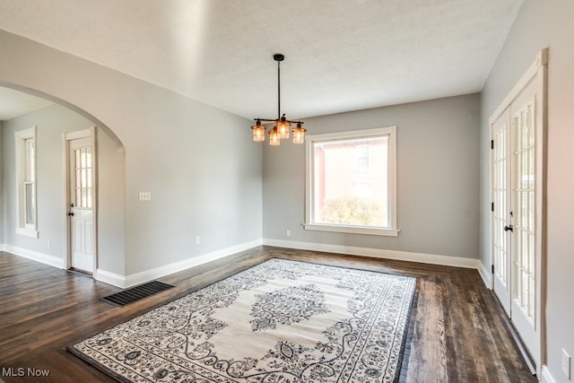 unfurnished room with french doors, a textured ceiling, a notable chandelier, and dark hardwood / wood-style flooring