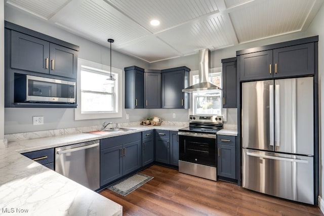 kitchen featuring wall chimney range hood, dark hardwood / wood-style flooring, appliances with stainless steel finishes, decorative light fixtures, and light stone counters