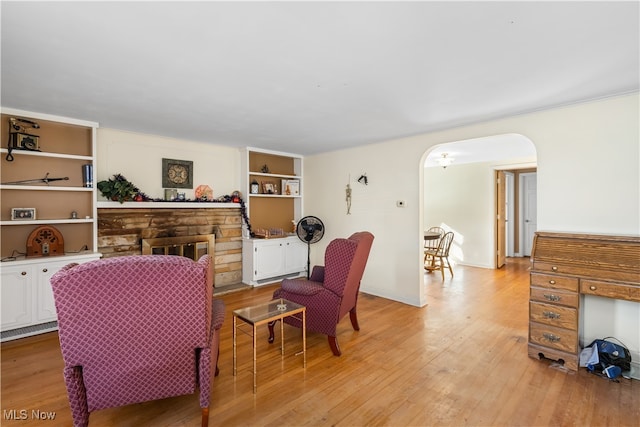 living room with light hardwood / wood-style floors, a fireplace, and built in shelves