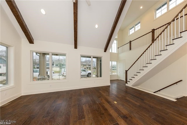 unfurnished living room featuring beam ceiling, dark wood-type flooring, and a wealth of natural light